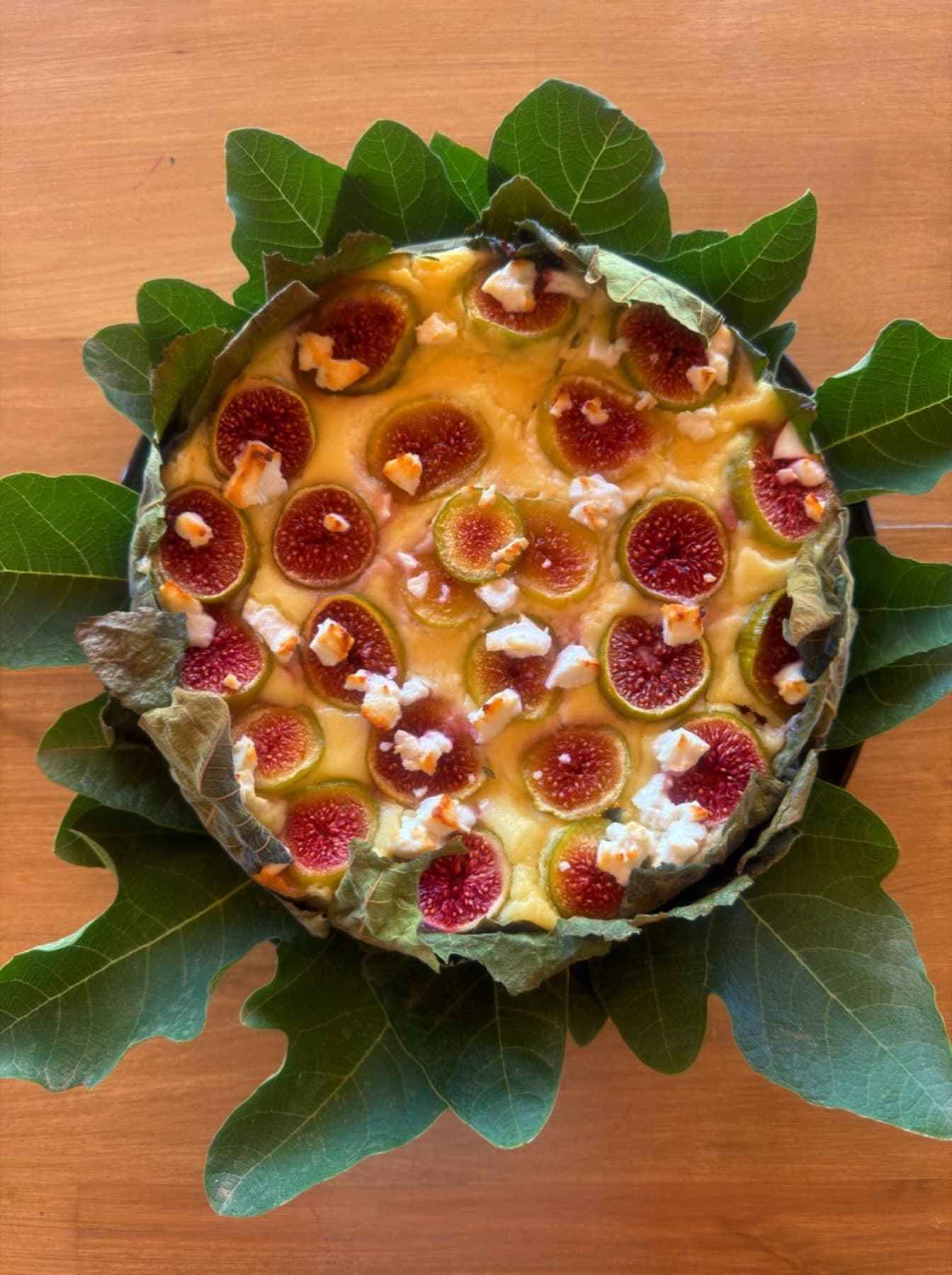 Tarta de higos de la finca, sobre hojas, en una mesa de madera.